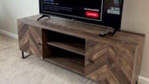 Un téléviseur à écran plat posé sur un meuble de télévision en bois, doté d’étagères.