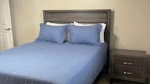 Une chambre à coucher avec un lit, une table de chevet et un ventilateur de plafond.