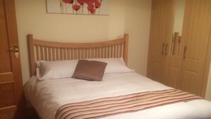 A bedroom with a wooden bed, white bedding, a striped throw, and a painting of red flowers on the wall. - STRUTHAN BEAG DINGLE (Dingle)