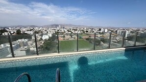 A swimming pool with a city view, clear sky, and distant mountains. -  Miraflores 1BR Apartment | Rooftop Pool, WiFi, Co-Work & City Views (Miraflores)