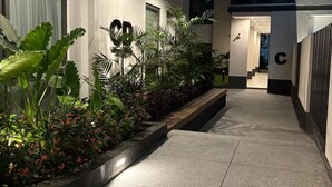 Um edifício moderno com entrada bem iluminada, um grande sinal em formato de 'C' e um caminho que leva a uma escadaria.