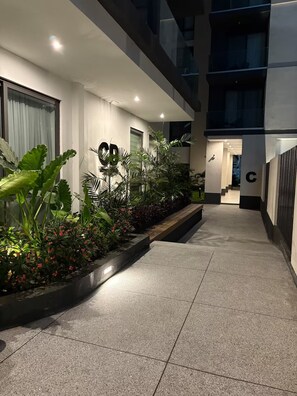 A modern building with a well-lit entrance, a large 'C' sign, and a pathway leading to a staircase. - Cozy 1-bedroom apartment with AC in pleasant Accra (Accra)