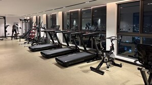 Academia com esteiras, bicicletas ergométricas e aparelhos de musculação.