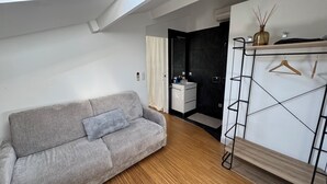 A modern room with a grey sofa, a wooden floor, a white wardrobe with a hanger, and a black door. - Private cocoon & swimming pool Absolute calm (Rognonas)