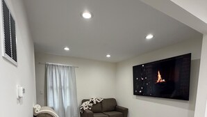 Una sala de estar moderna con un sofá seccional, una mesa de centro, un televisor de pantalla plana y luces empotradas en el techo.
