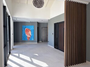 Ein geräumiger Flur mit moderner Decke, einem großen abstrakten Gemälde und einer Holzvertäfelung an der rechten Seite.