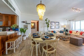 A dining area with a chandelier, wooden chairs, a round table, and a kitchen with wooden cabinets and a countertop. - Family Beach Escape | Playa Las Ballenas | Private Pool & Terrace (Las Terrenas)