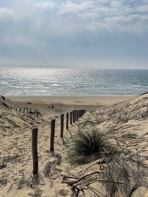A sandy beach with a wooden fence and sparse vegetation. - La Casa du Bassin (Lège-Cap-Ferret)