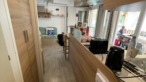 Un corridoio stretto che conduce a una zona cucina con mobili in legno, un tavolo da pranzo e vista sull'esterno.