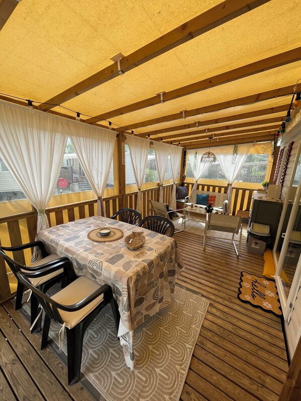 A covered outdoor dining area with a table, chairs, and a view of the outdoors.