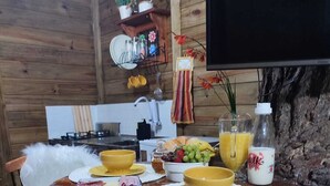 Un interior de madera con una mesa redonda de comedor, sillas, una zona de cocina y un televisor montado.
