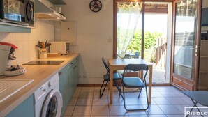 Cocina compacta equipada con lavadora, microondas y comedor con mesa y sillas.