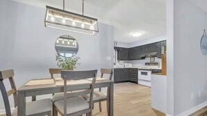 Une cuisine moderne avec des meubles de couleur sombre, un plan de travail blanc et un luminaire suspendu.