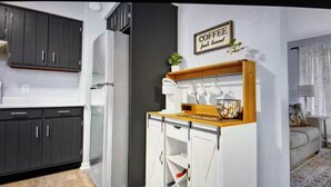 Une cuisine compacte équipée d’un réfrigérateur, d’un coin café et d’un petit espace repas.