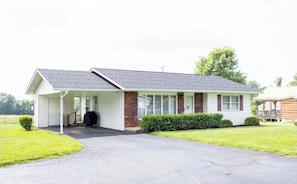 A single-story house with a covered porch, a garage, and a well-maintained lawn.