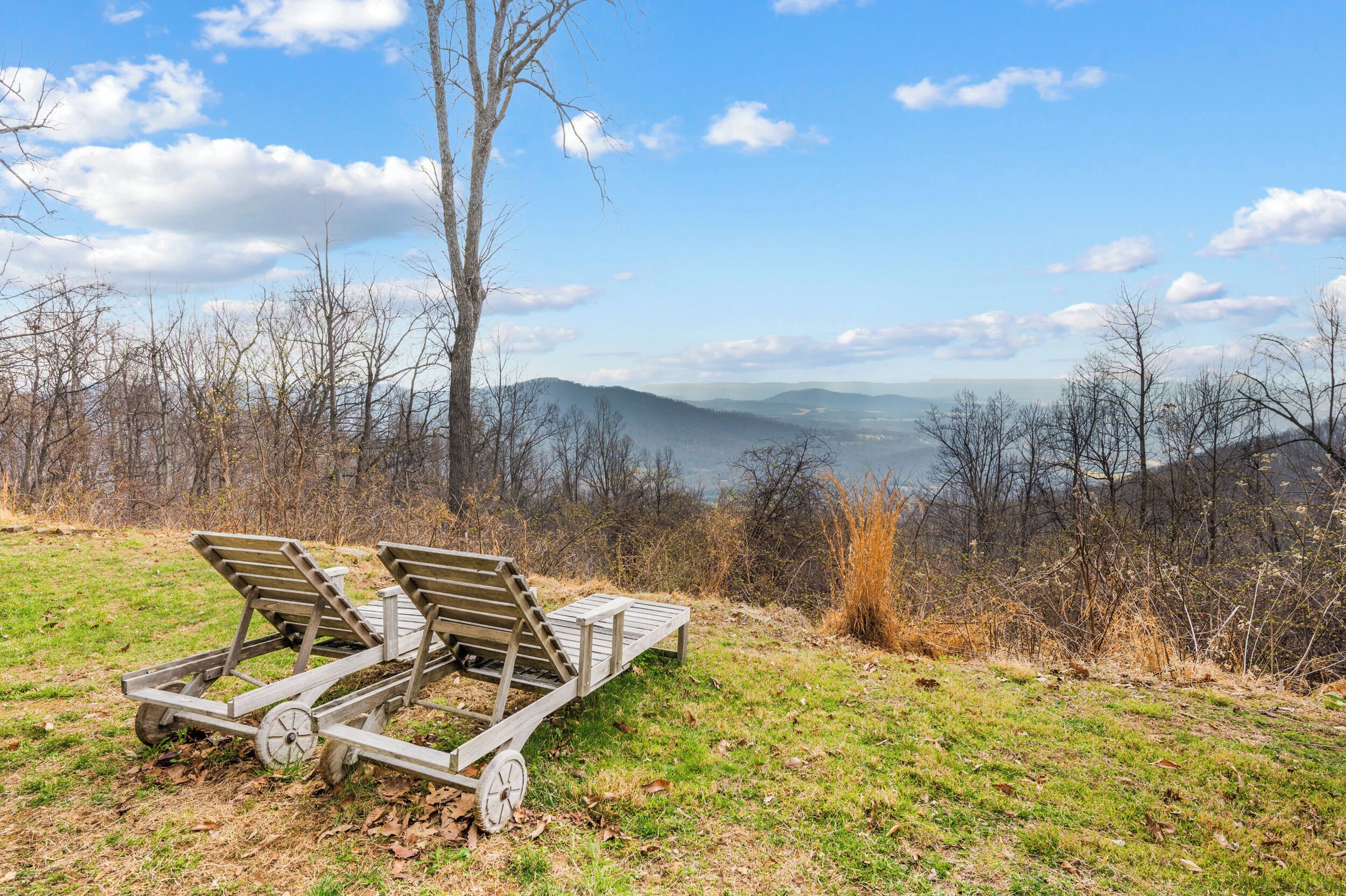 A wooden deck with two lounge chairs overlooking a scenic landscape.