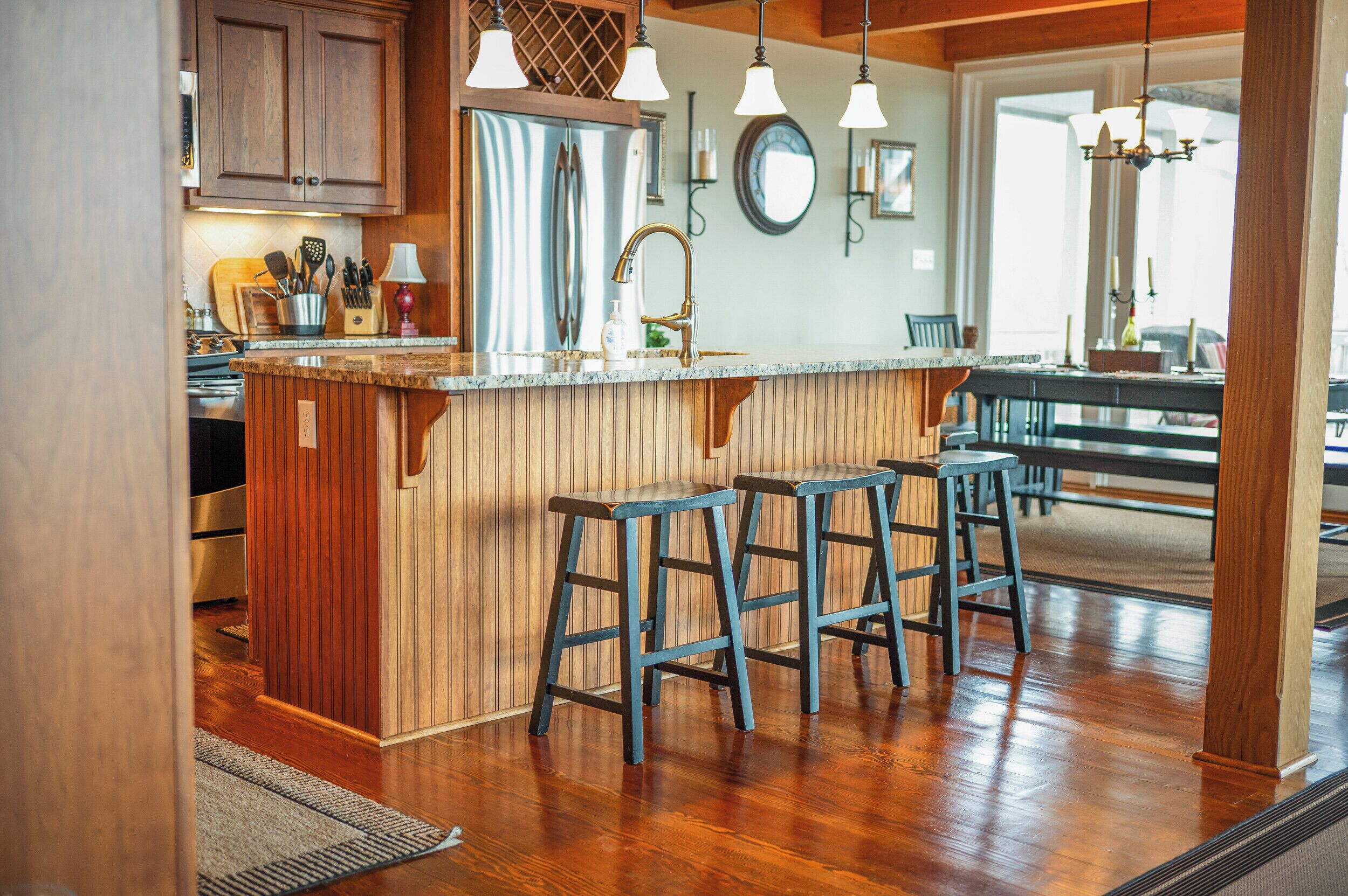 A kitchen with wooden cabinets, a central island with stools, stainless steel appliances, and pendant lighting.