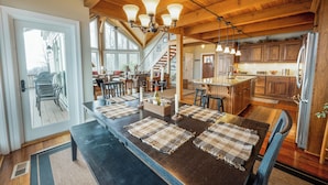 Une cuisine spacieuse dotée de meubles en bois, d’un réfrigérateur en acier inoxydable et d’un coin repas avec une longue table et des bancs.