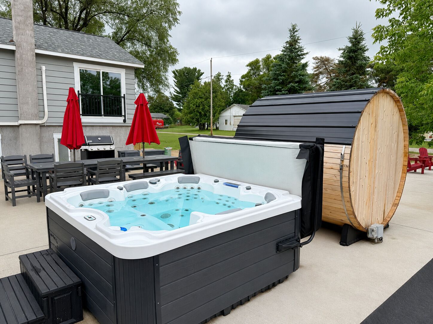 A hot tub with a wooden barrel, outdoor furniture, and a grill.