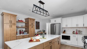 Una cucina moderna con mobili in legno, un piano di lavoro bianco, un frigorifero in acciaio inossidabile e un forno a microonde integrato.