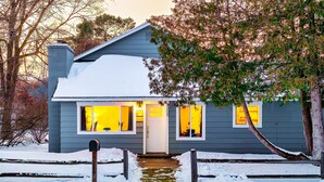 Una casa con tetto innevato, una cassetta delle lettere e un piccolo giardino anteriore con una recinzione in legno.
