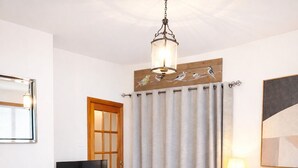 Un salon avec une cheminée, un téléviseur, un canapé, un pouf rond et une lampe.