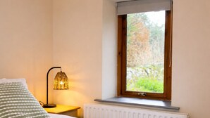Une chambre à coucher avec un lit, une lampe de chevet, une fenêtre et un radiateur.