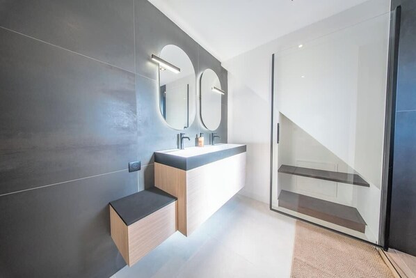 Un baño moderno con un espejo grande, un lavabo y un box de ducha de vidrio.