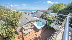 A deck with a hot tub, lounge chairs, and a view of the ocean. - Villa pieds dans l'eau - vue mer & jacuzzi (Larmor-Plage)