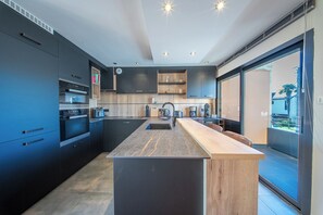 Una cocina moderna con armarios oscuros, una isla central y un amplio ventanal.