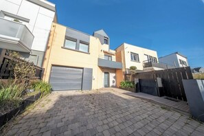 A modern residential building with a paved driveway, a garage, and a fenced backyard. - Villa pieds dans l'eau - vue mer & jacuzzi (Larmor-Plage)