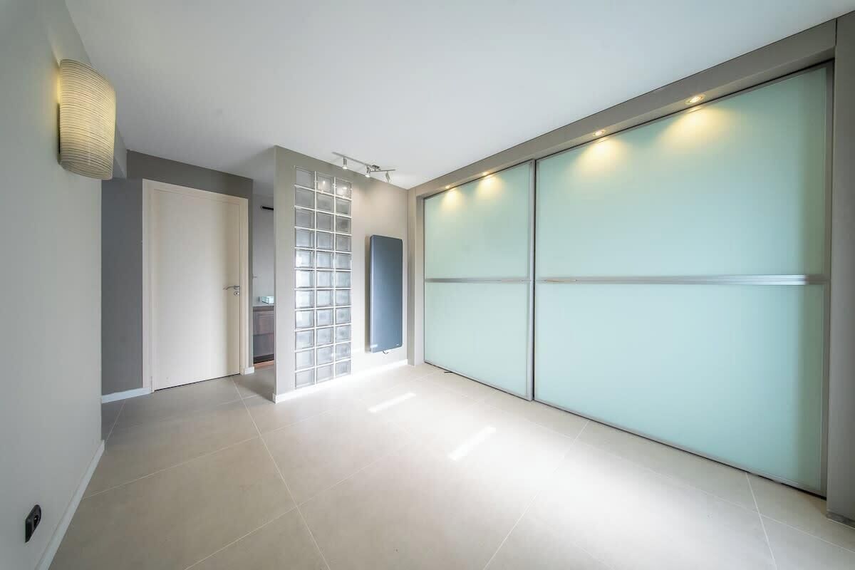 A hallway with a sliding door, a light fixture, and a glass partition.