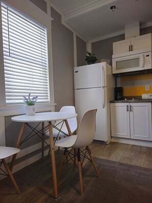 Eine kompakte Küche mit Kühlschrank, Mikrowelle und einer kleinen Essecke mit Tisch und Stühlen.