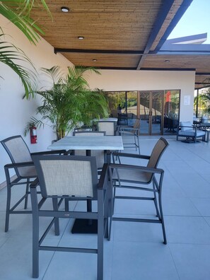 An outdoor patio area with tables and chairs, a fire extinguisher, and potted plants. - Stunning new Beachfront Condo 9th Floor Ocean View (Jacó)