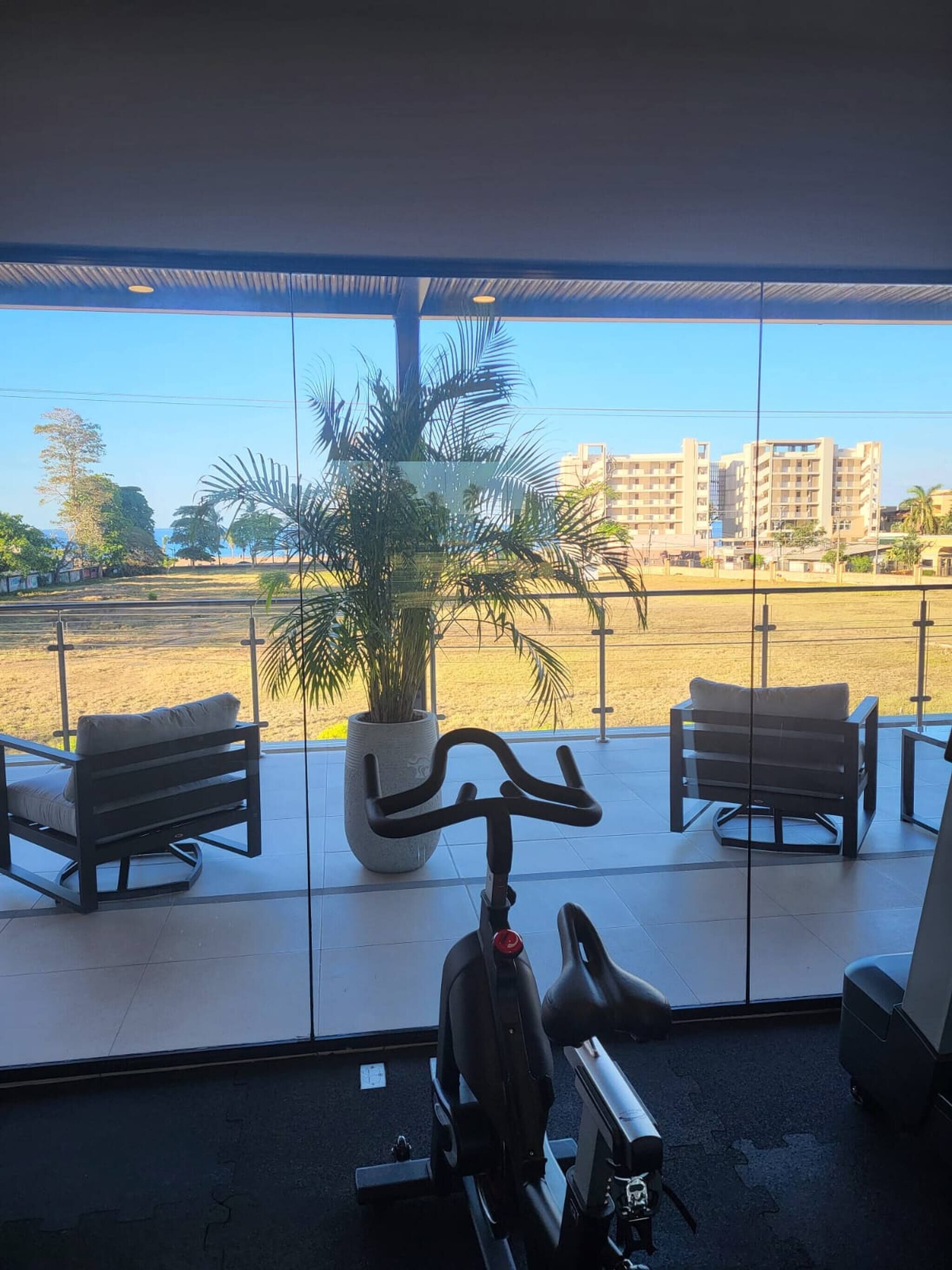 A balcony with two chairs, a stationary exercise bike, and a potted plant.
