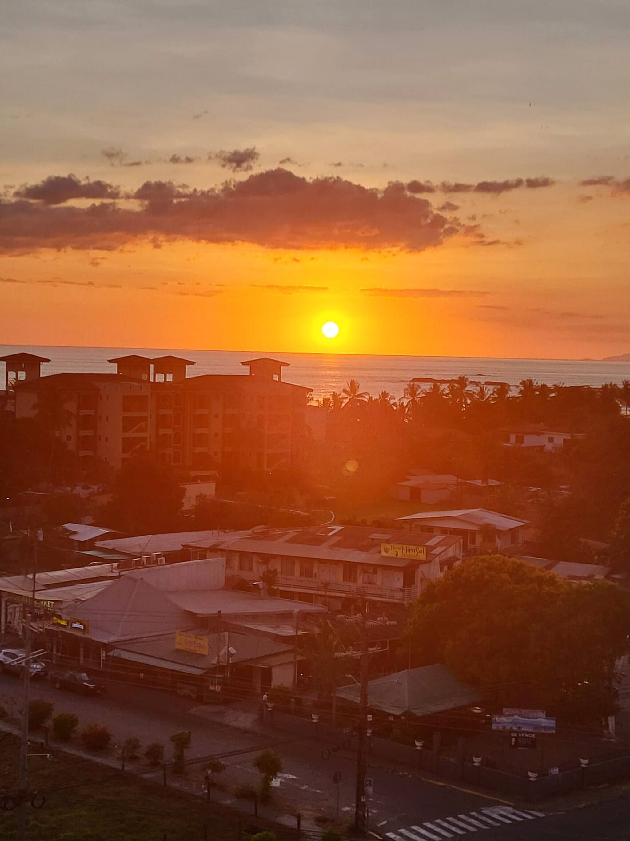 A coastal town at sunset with buildings and a clear view of the ocean.