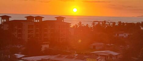 A coastal town at sunset with buildings and a clear view of the ocean.