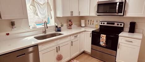 Una cocina moderna con armarios blancos, electrodomésticos de acero inoxidable, lavavajillas y una alfombra con motivos florales.