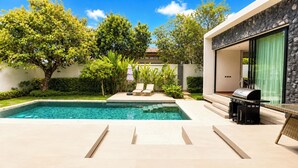 A modern outdoor pool area with a clear blue pool, lounge chairs, and a barbecue grill. - Villa Luma Botanica | Private Pool Villa Near Bang Tao Beach (Tambon Choeng Thale)