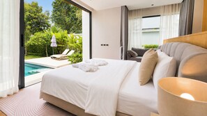Ein modernes Hotelzimmer mit einem großen Bett, Blick auf einen Swimmingpool und einem Balkon mit Gartenmöbeln.