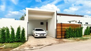 A modern house with a garage, a white car parked inside, and a clear blue sky. - Villa Luma Botanica | Private Pool Villa Near Bang Tao Beach (Tambon Choeng Thale)