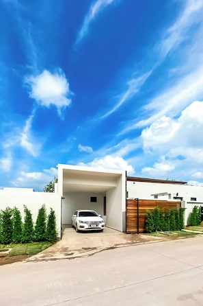 Ein modernes Haus mit Garage, ein weißes Auto steht darin abgestellt, und ein klarer, blauer Himmel.