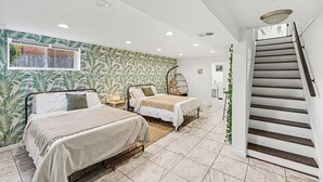 Un dormitorio con dos camas, una ventana, una escalera y una pared con un diseño de hojas.