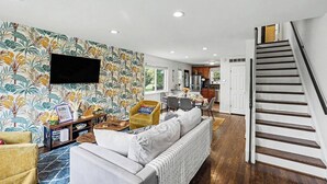Una sala de estar moderna con un sofá, un sillón y un televisor montado en la pared.