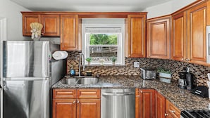 Una cocina con armarios de madera, electrodomésticos de acero inoxidable, encimera de granito y ventana con vistas.