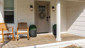A house with a porch, a door with a wreath, two potted plants, and two chairs. - Near Benning, Steps to Riverwalk/Bibb Mill, 2 Kings, Queen Sofa Bed, Sleeps 6 (Columbus)