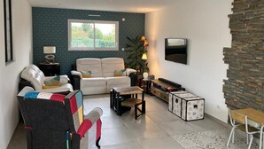 Una sala de estar con sofá, sillones, una mesa de centro, televisor y una pared de acento de piedra.