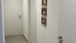 Un pasillo con paredes blancas, piso de baldosas y tres cuadros enmarcados en la pared.
