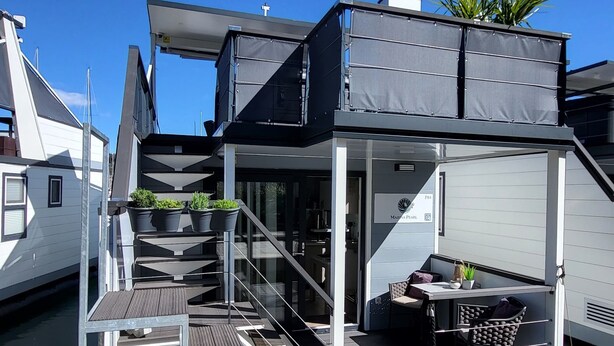 Une terrasse extérieure moderne avec un escalier menant à un espace salon abrité.