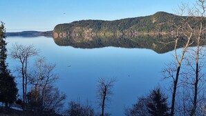 A calm lake with a forested island in the center, surrounded by trees.